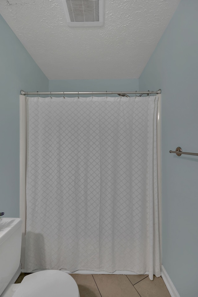 bathroom featuring toilet, a textured ceiling, and tile patterned flooring