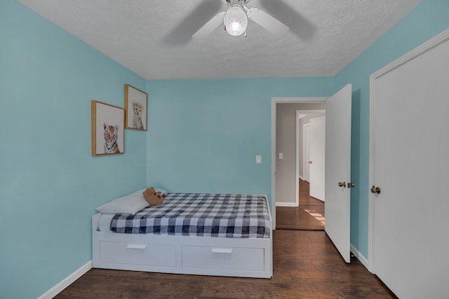 bedroom with dark hardwood / wood-style flooring, a textured ceiling, and ceiling fan