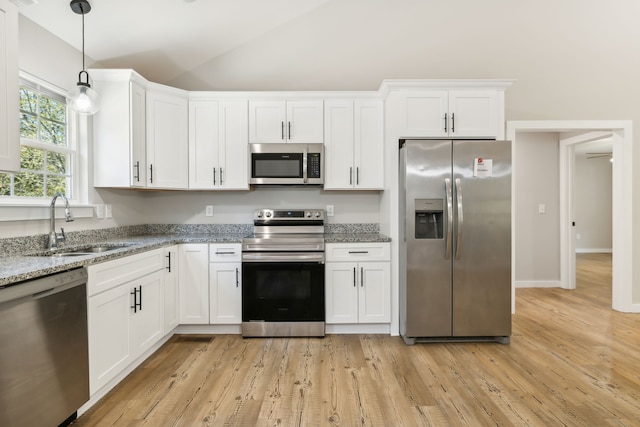 kitchen featuring light stone counters, appliances with stainless steel finishes, lofted ceiling, and white cabinets