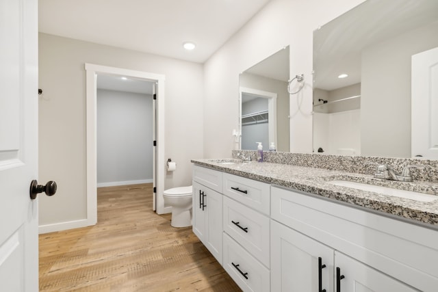 bathroom featuring toilet, walk in shower, hardwood / wood-style flooring, and vanity