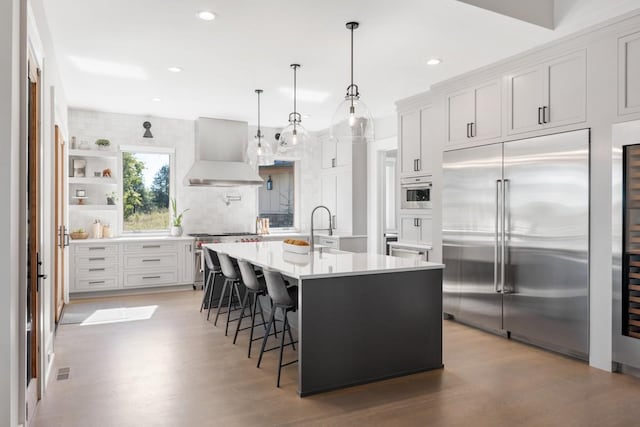 5893 Cairo Bend Rd, Lebanon, TN 37087 - kitchen with high quality appliances, wall chimney exhaust hood, backsplash, a breakfast bar, and a sink