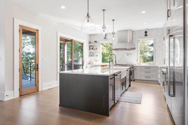 5893 Cairo Bend Rd, Lebanon, TN 37087 - kitchen with wall chimney range hood, high end appliances, light wood finished floors, light countertops, and decorative backsplash