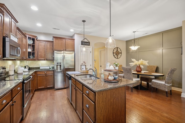 kitchen featuring a center island with sink, hanging light fixtures, hardwood / wood-style flooring, sink, and stainless steel appliances