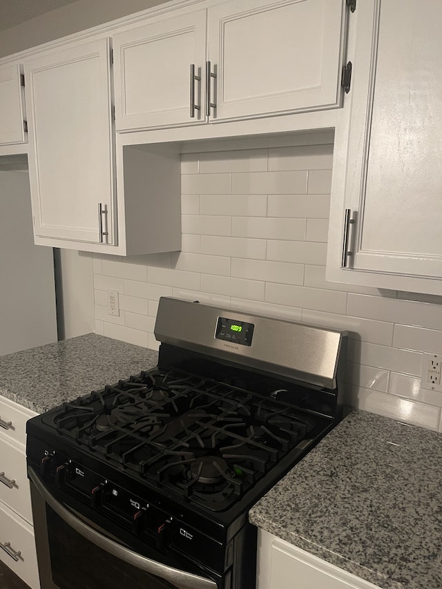 kitchen featuring decorative backsplash, white cabinetry, light stone counters, and stainless steel gas range