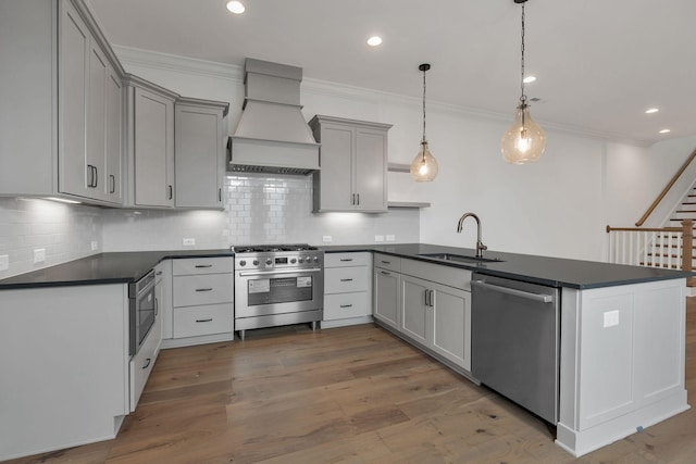 kitchen featuring dark countertops, custom range hood, a peninsula, stainless steel appliances, and a sink