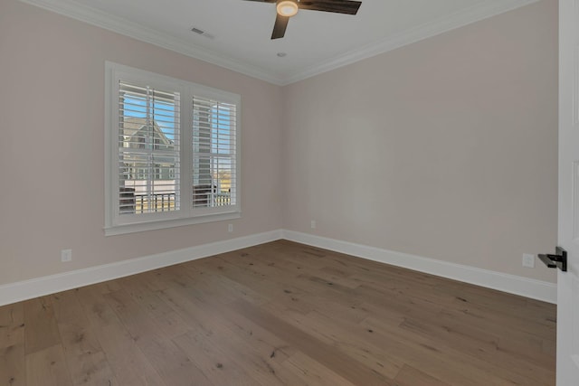 spare room with visible vents, crown molding, baseboards, and wood finished floors