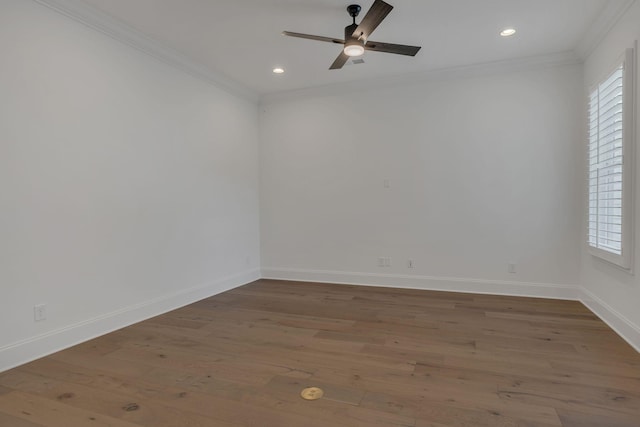 empty room with a wealth of natural light, crown molding, and wood finished floors