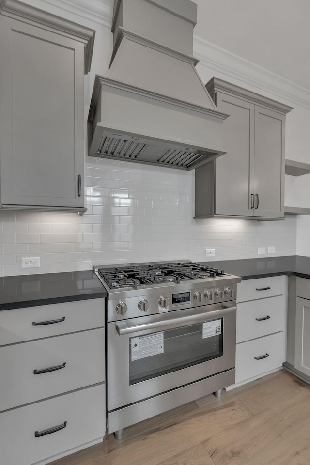 kitchen featuring open shelves, dark countertops, light wood-type flooring, premium range hood, and stainless steel gas range oven