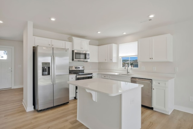 kitchen featuring white cabinets, a kitchen island, appliances with stainless steel finishes, light hardwood / wood-style floors, and sink