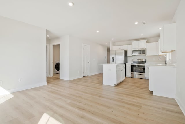 kitchen with light hardwood / wood-style floors, appliances with stainless steel finishes, a center island, and white cabinets