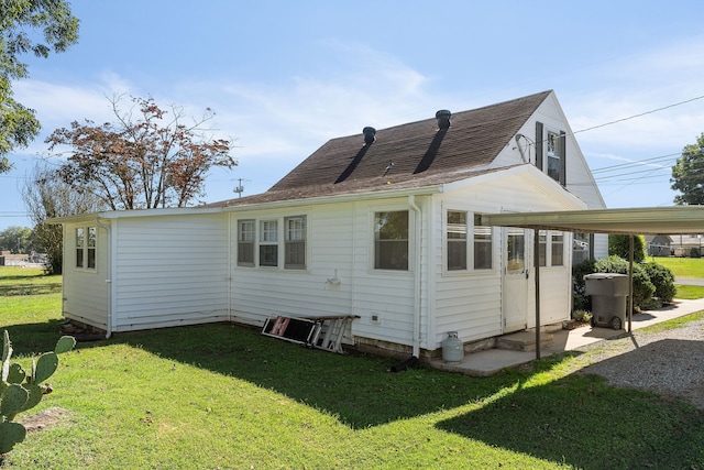 rear view of property featuring a lawn and a carport