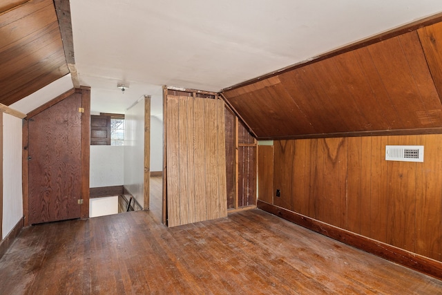 additional living space featuring vaulted ceiling, wooden walls, and hardwood / wood-style floors