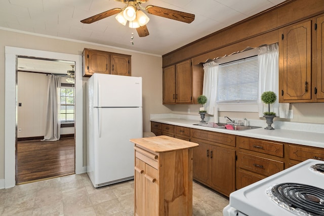 kitchen with white appliances, ornamental molding, sink, light hardwood / wood-style floors, and ceiling fan