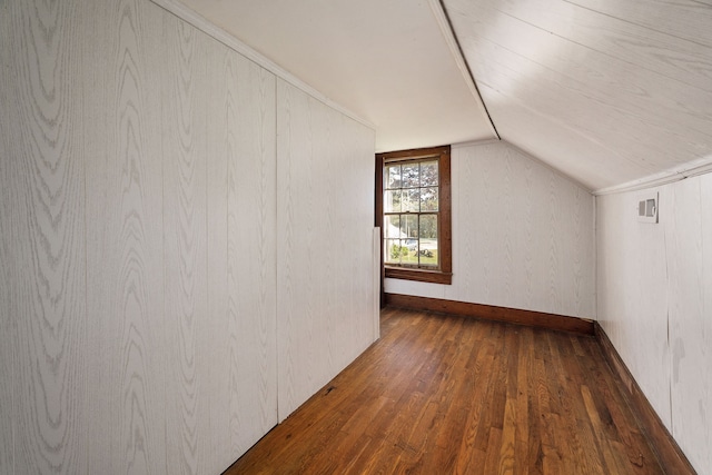 additional living space featuring vaulted ceiling, wood walls, and dark hardwood / wood-style flooring