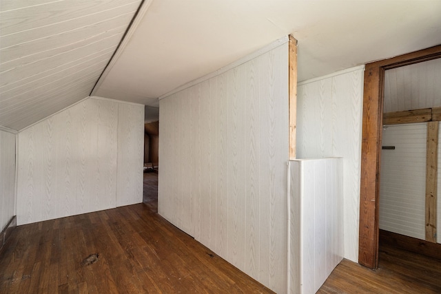 additional living space featuring wood walls, lofted ceiling, and dark hardwood / wood-style flooring