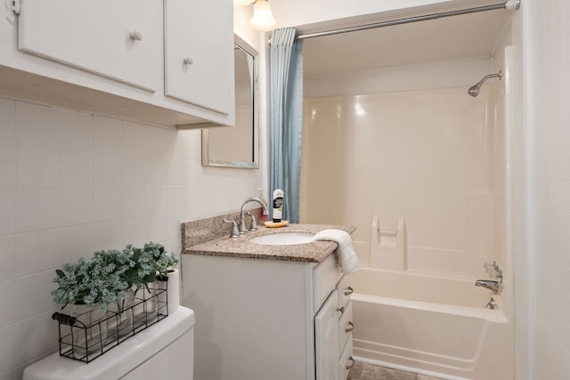 full bathroom with vanity, toilet, tile walls, and tub / shower combination