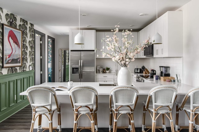 kitchen featuring kitchen peninsula, stainless steel fridge, dark hardwood / wood-style flooring, white cabinets, and tasteful backsplash