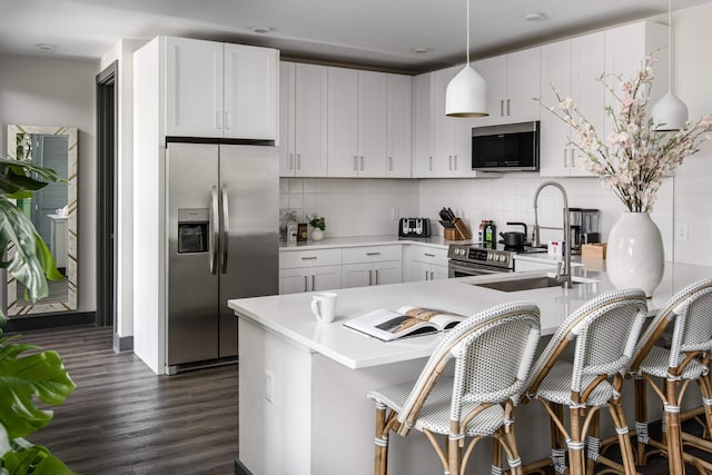 kitchen with kitchen peninsula, white cabinets, stainless steel appliances, and hanging light fixtures