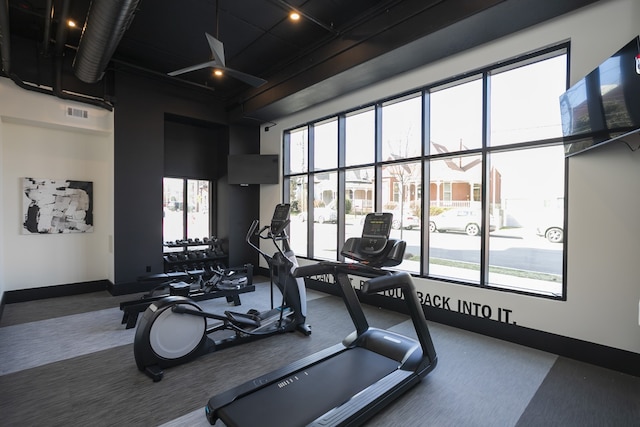 gym with a healthy amount of sunlight, a high ceiling, and carpet floors