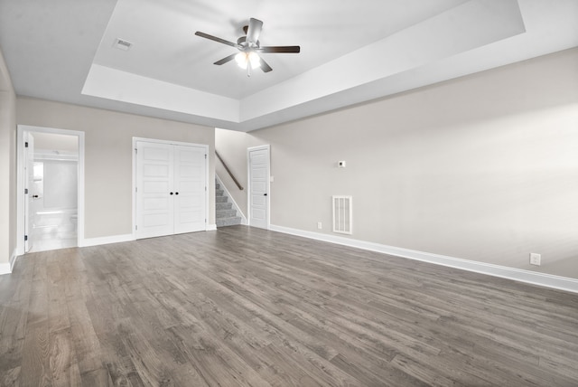 interior space featuring ceiling fan, dark hardwood / wood-style floors, and a tray ceiling