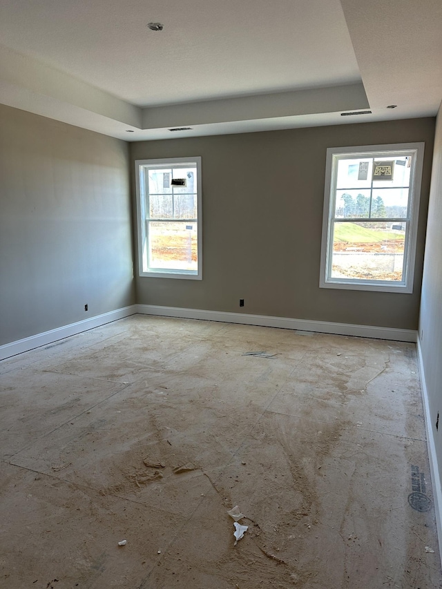 unfurnished room with a tray ceiling and a healthy amount of sunlight