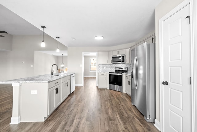 kitchen with stainless steel appliances, a kitchen island with sink, dark wood-type flooring, sink, and pendant lighting