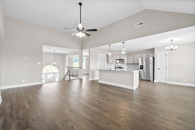 unfurnished living room with dark hardwood / wood-style floors, ceiling fan with notable chandelier, and high vaulted ceiling