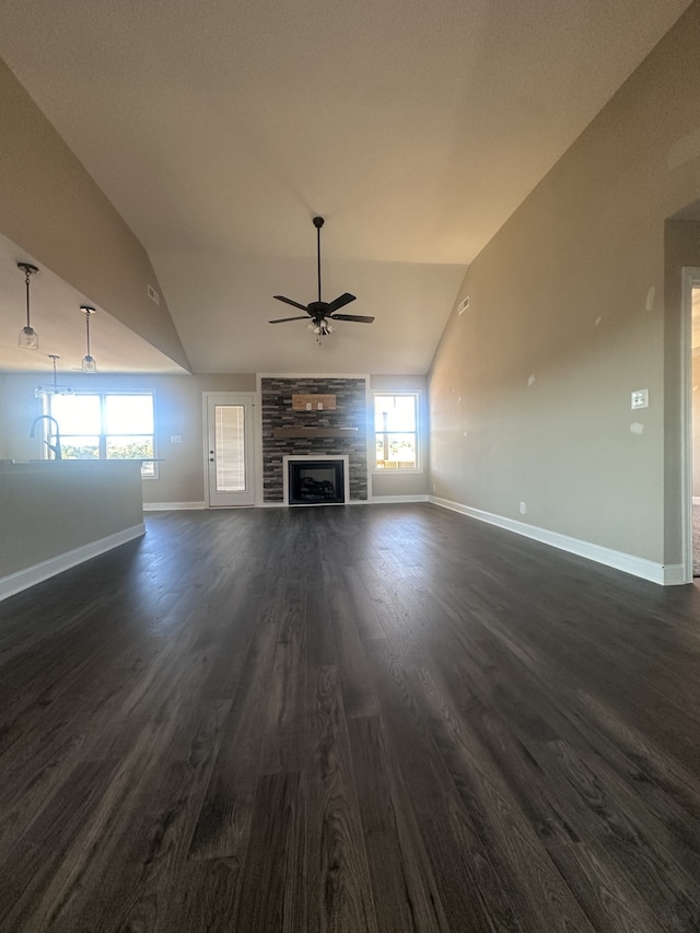 unfurnished living room with dark hardwood / wood-style flooring, vaulted ceiling, ceiling fan, and a stone fireplace