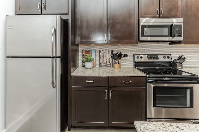 kitchen with light stone countertops, stainless steel appliances, dark brown cabinets, and decorative backsplash