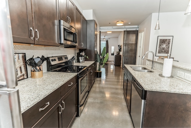 kitchen with sink, a barn door, backsplash, stainless steel appliances, and pendant lighting