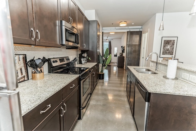 210 30th Ave N Unit 209, Nashville, TN 37203 - kitchen featuring dark brown cabinets, appliances with stainless steel finishes, a sink, a kitchen island with sink, and decorative backsplash