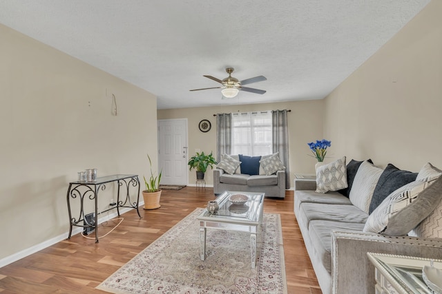 living room with light hardwood / wood-style floors, a textured ceiling, and ceiling fan