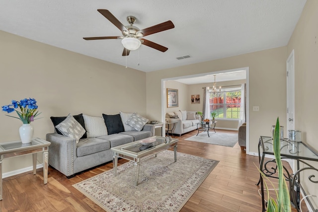 living room with ceiling fan with notable chandelier and light wood-type flooring