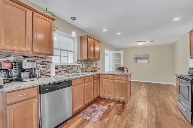 kitchen with light hardwood / wood-style flooring, kitchen peninsula, stainless steel appliances, sink, and decorative light fixtures