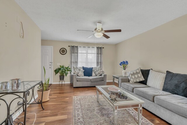 living room with a textured ceiling, hardwood / wood-style flooring, and ceiling fan