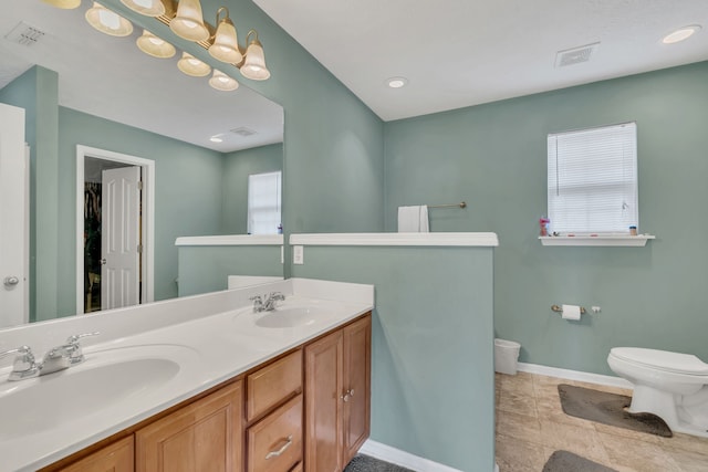 bathroom with a wealth of natural light, vanity, toilet, and tile patterned floors