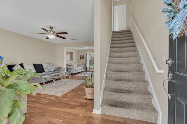 staircase with wood-type flooring and ceiling fan with notable chandelier