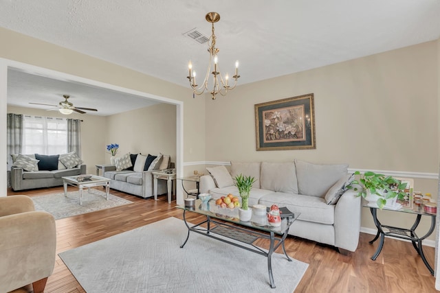 living room with hardwood / wood-style flooring and ceiling fan with notable chandelier