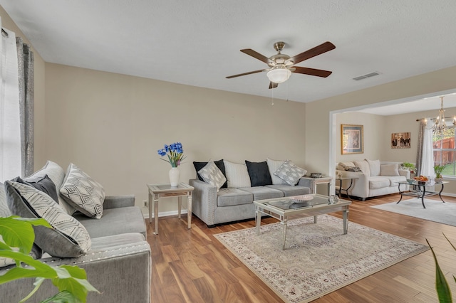 living room featuring light hardwood / wood-style floors and ceiling fan with notable chandelier