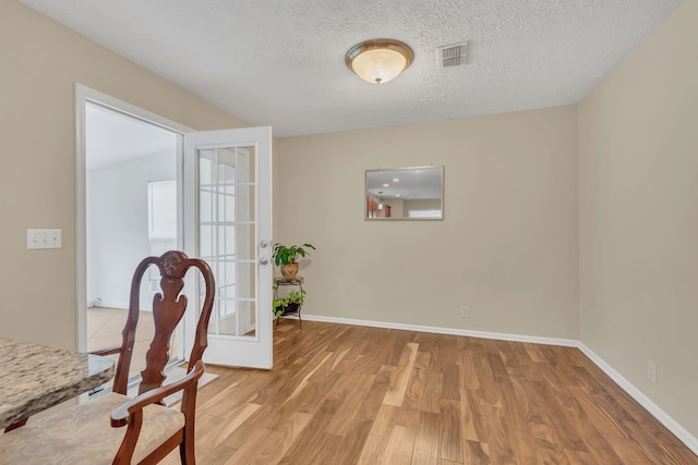 home office featuring french doors, light hardwood / wood-style flooring, and a textured ceiling