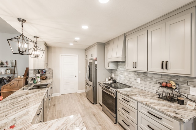 kitchen featuring appliances with stainless steel finishes, sink, pendant lighting, custom range hood, and light hardwood / wood-style flooring