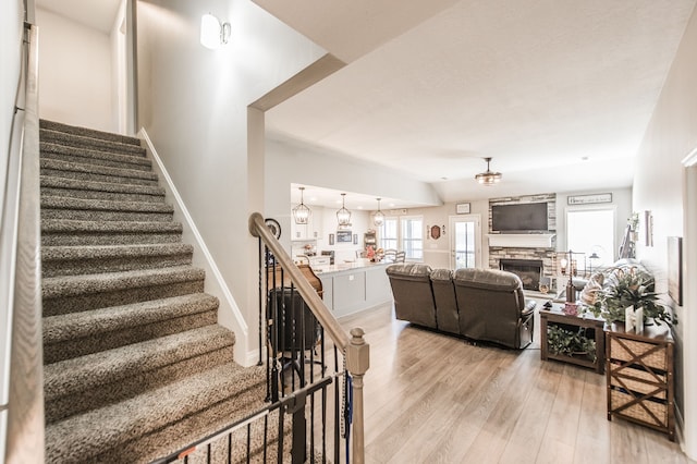 stairway featuring hardwood / wood-style floors and a fireplace