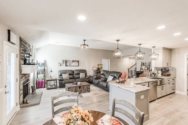 kitchen featuring light hardwood / wood-style flooring, light stone counters, hanging light fixtures, and sink