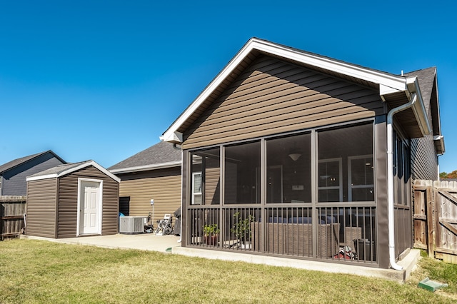 rear view of house featuring a shed, a yard, a sunroom, a patio, and central air condition unit