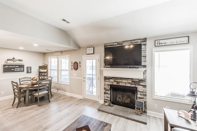 living room with vaulted ceiling, a fireplace, and light wood-type flooring