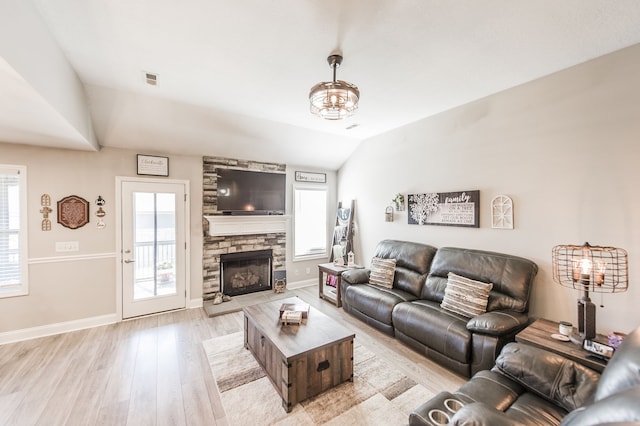 living room featuring vaulted ceiling, a fireplace, and light wood-type flooring