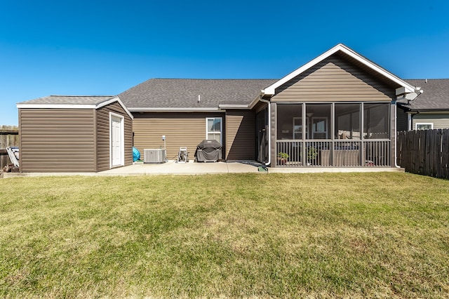 back of property with a storage unit, a sunroom, central AC unit, a patio area, and a lawn