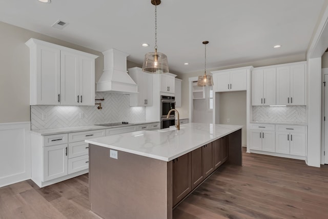 kitchen featuring custom exhaust hood, dark hardwood / wood-style floors, white cabinets, and an island with sink