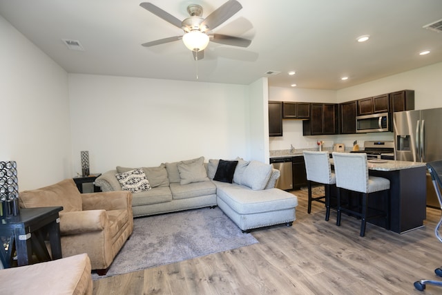 living room with light hardwood / wood-style floors and ceiling fan