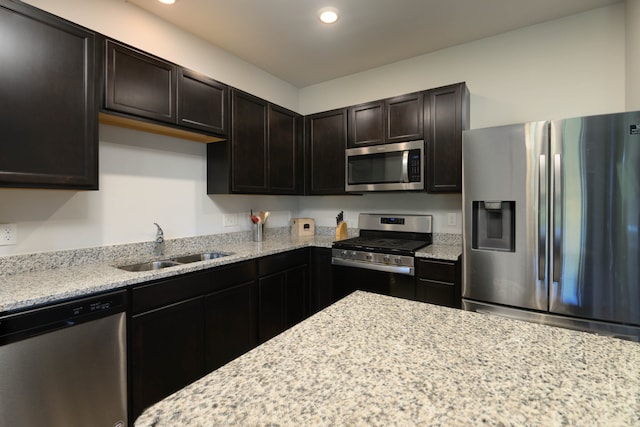 kitchen featuring sink, light stone countertops, dark brown cabinetry, and stainless steel appliances